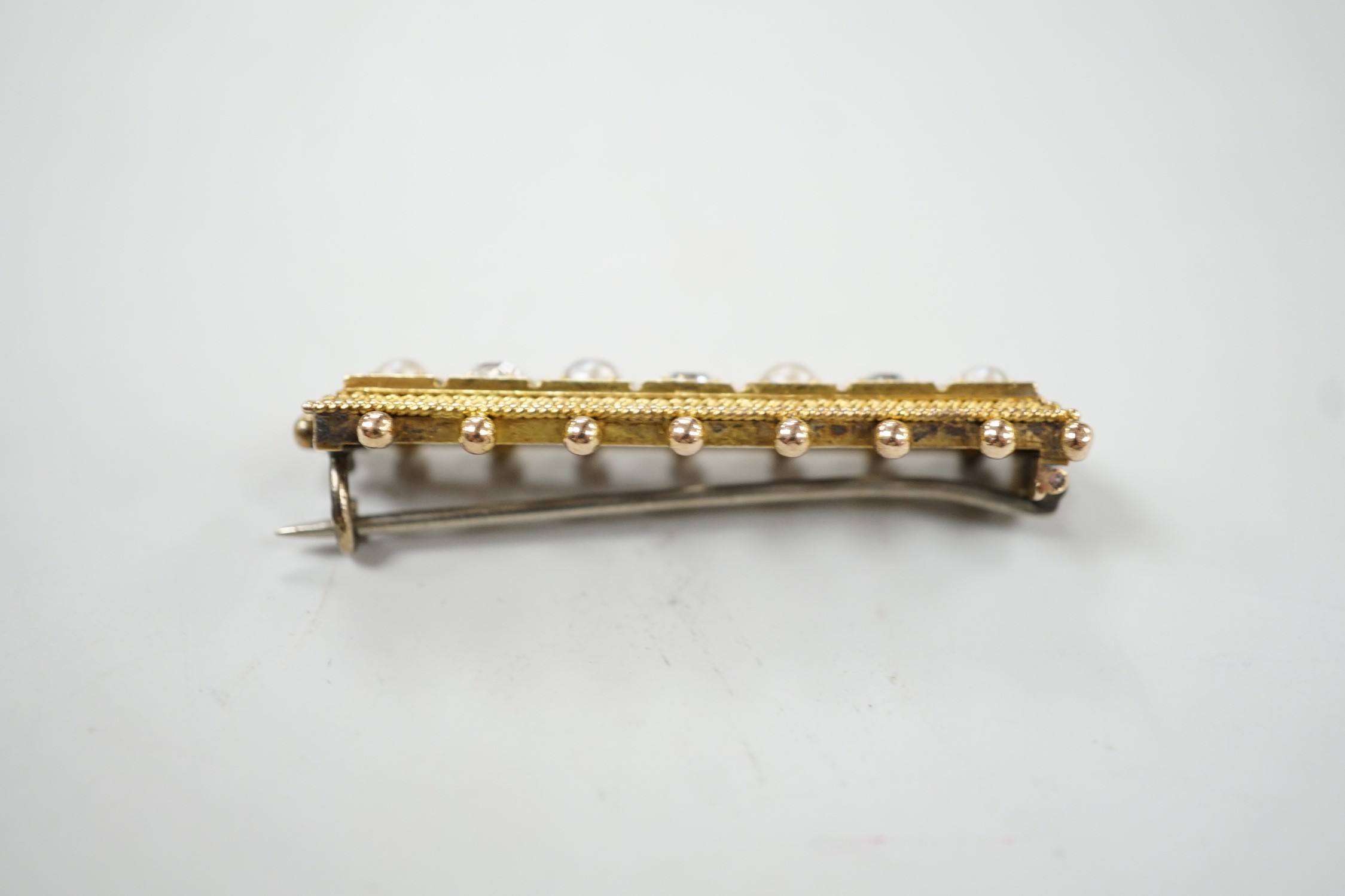 An early 20th century yellow metal, three stone diamond and four stone split pearl set bar brooch, 44mm, gross weight 6.8 grams.